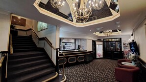 A hotel lobby with a grand staircase, a reception desk, and a chandelier. - Scarisbrick Hotel (Southport)