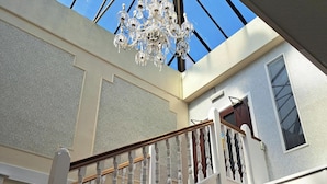 A grand staircase with a chandelier, leading to a second floor with a skylight. - Scarisbrick Hotel (Southport)