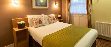 A hotel room with a neatly made bed, two bedside tables, a framed picture on the wall, and a window with curtains.