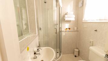 A bathroom with a glass-enclosed shower, a sink, a toilet, and a towel rack.