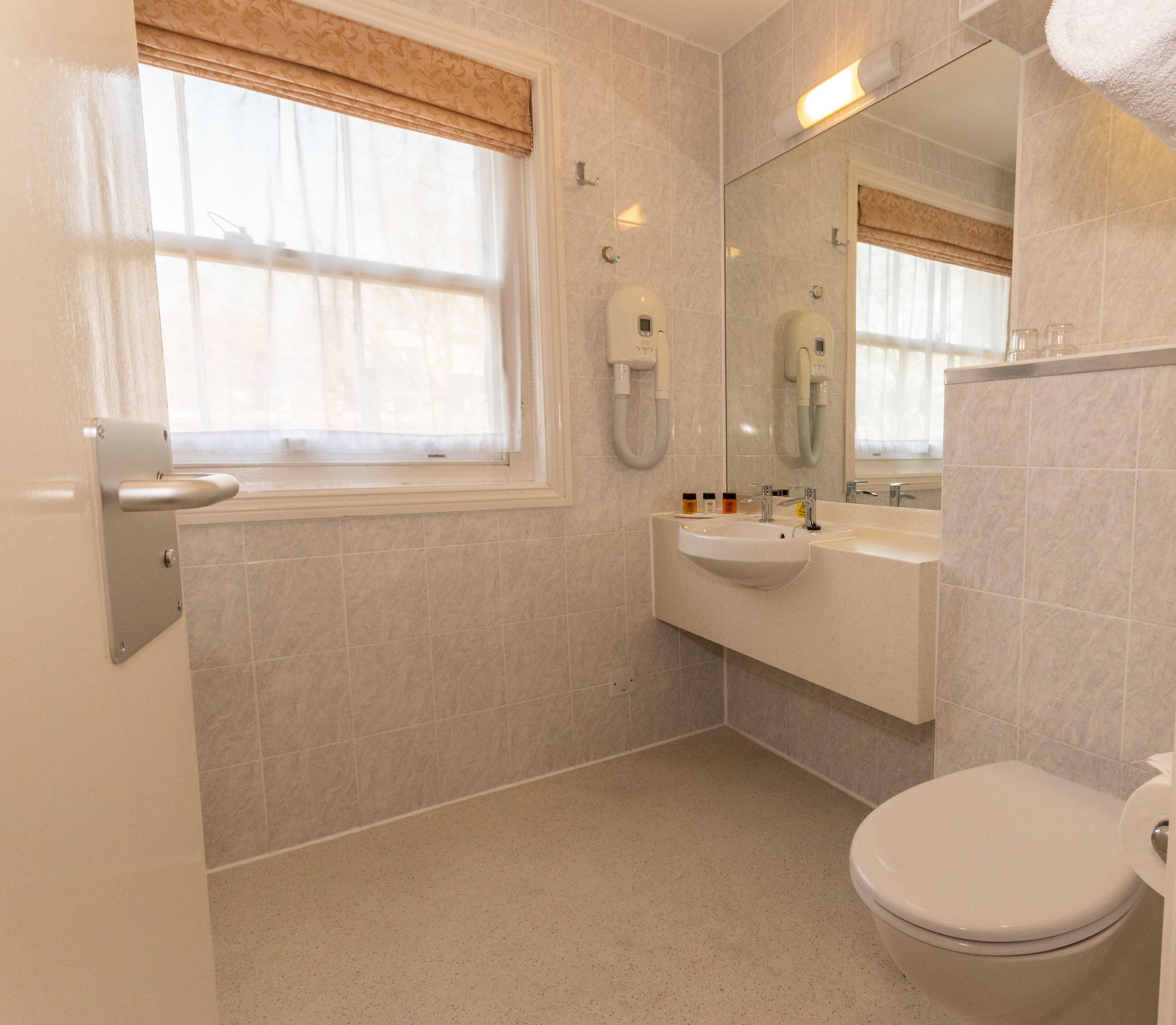 A bathroom with a toilet, sink, and a mirror.
