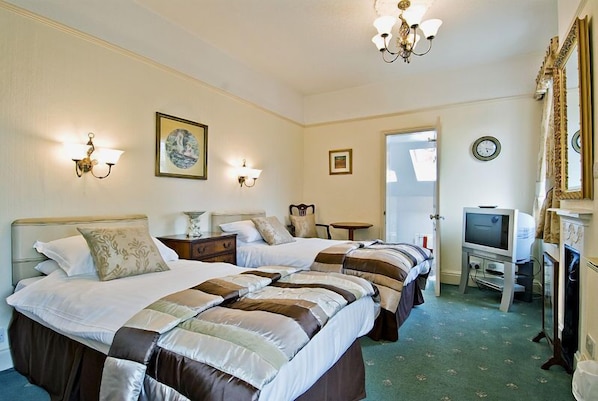 A hotel room with two beds, a television, a fireplace, and a large mirror.