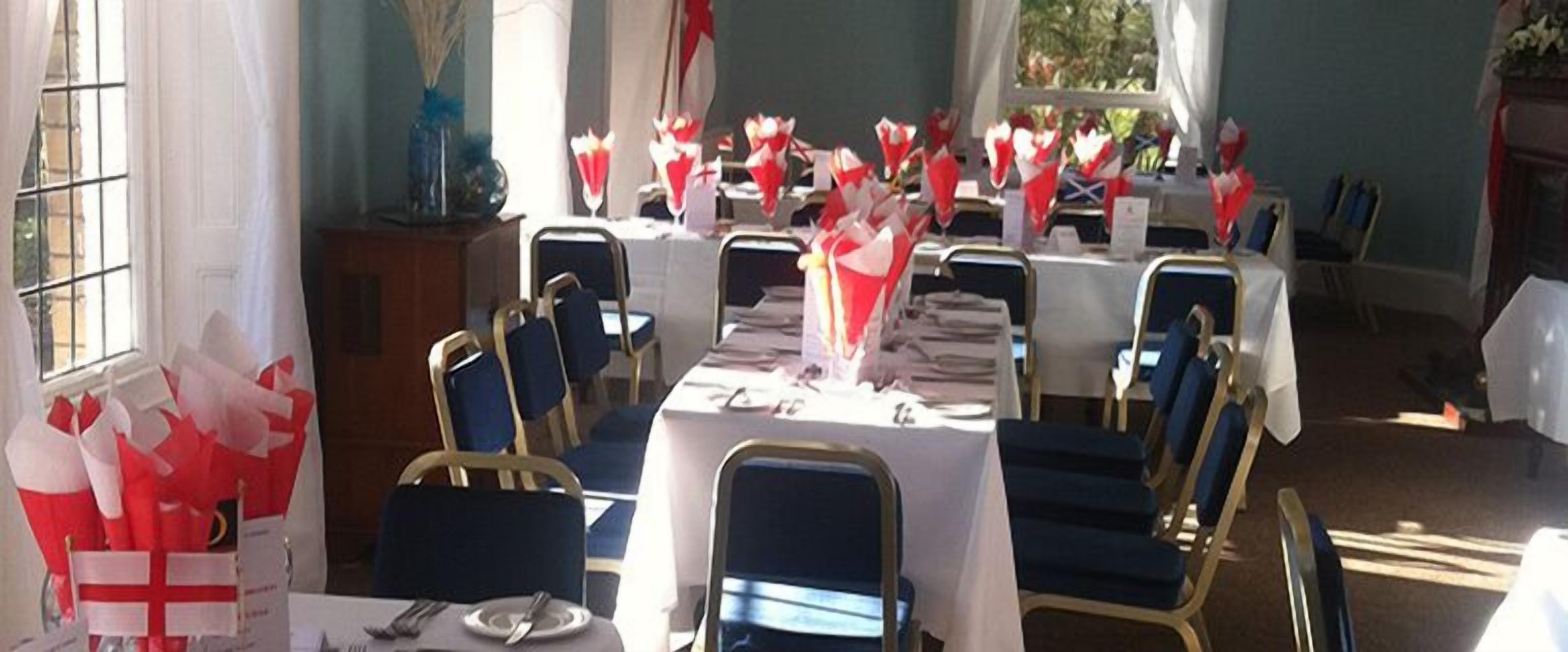 A dining area with tables set for a meal, chairs, and a window with curtains.