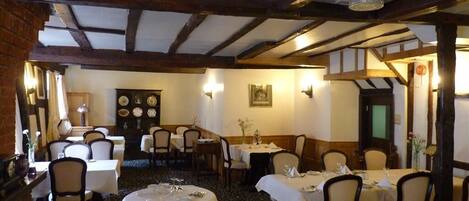 A traditional inn with wooden beams, round tables, and a cozy atmosphere.