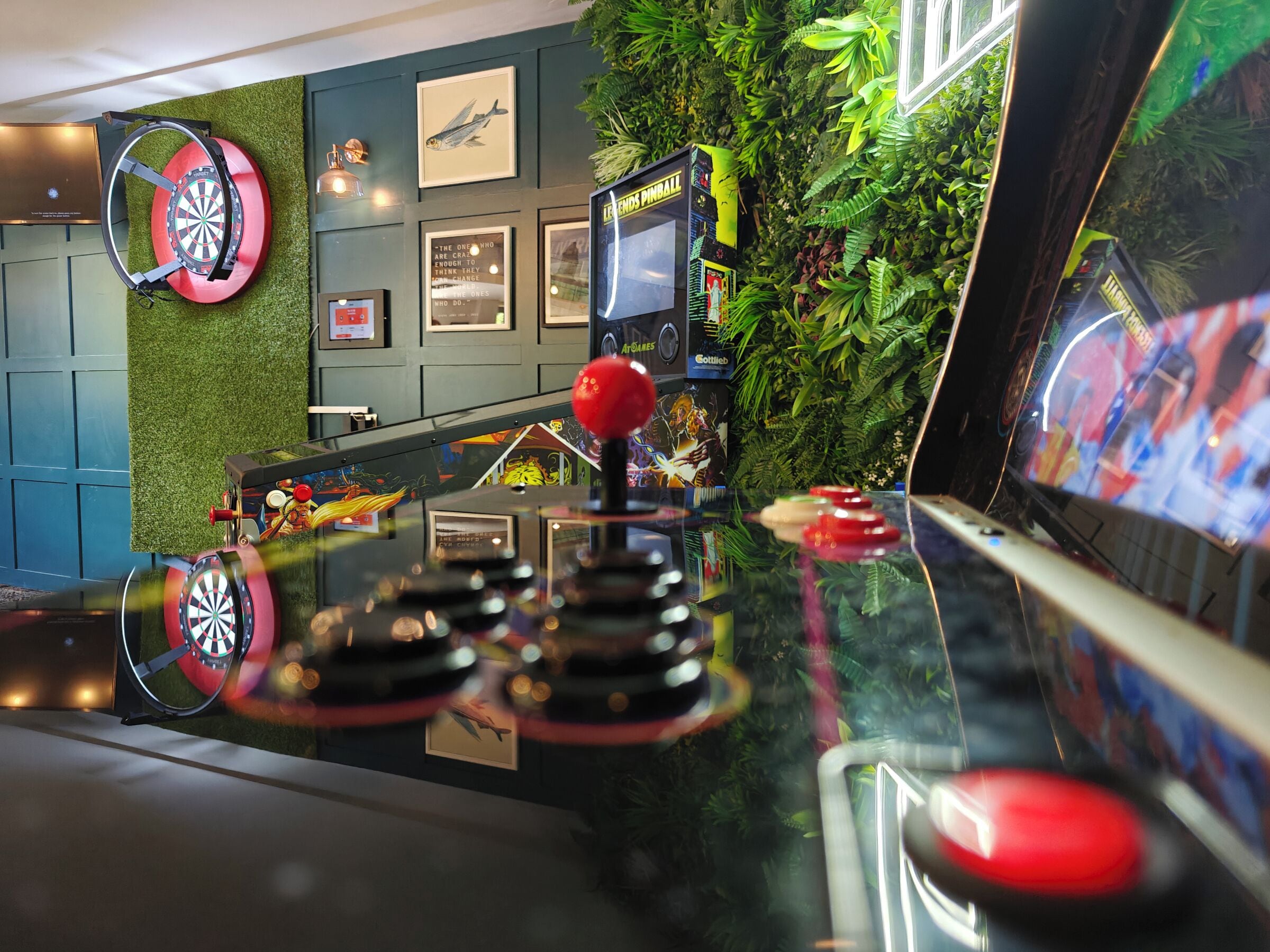 Un dardo fijado en una pared, junto con un atril y un tablero de dardos sobre la encimera.