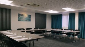 A conference room with a long table, chairs, and a painting on the wall.
