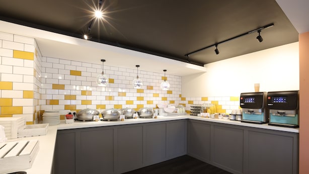 A modern kitchen with white and yellow tiles, grey cabinets, and stainless steel appliances. - Knowsley Inn & Lounge (Liverpool)
