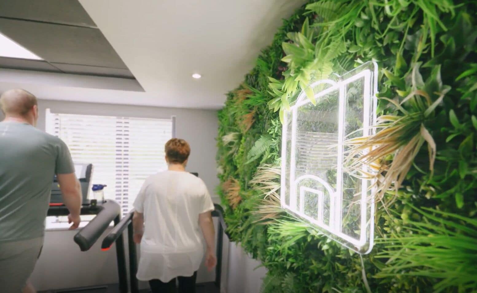 A gym with exercise equipment and a wall decorated with green plants.