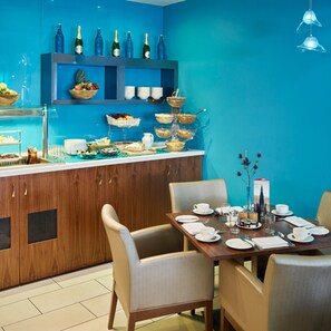 A modern dining area with a blue wall, wooden cabinets, and a buffet with various food items. - Hotel Indigo Edinburgh by IHG (Edinburgh)