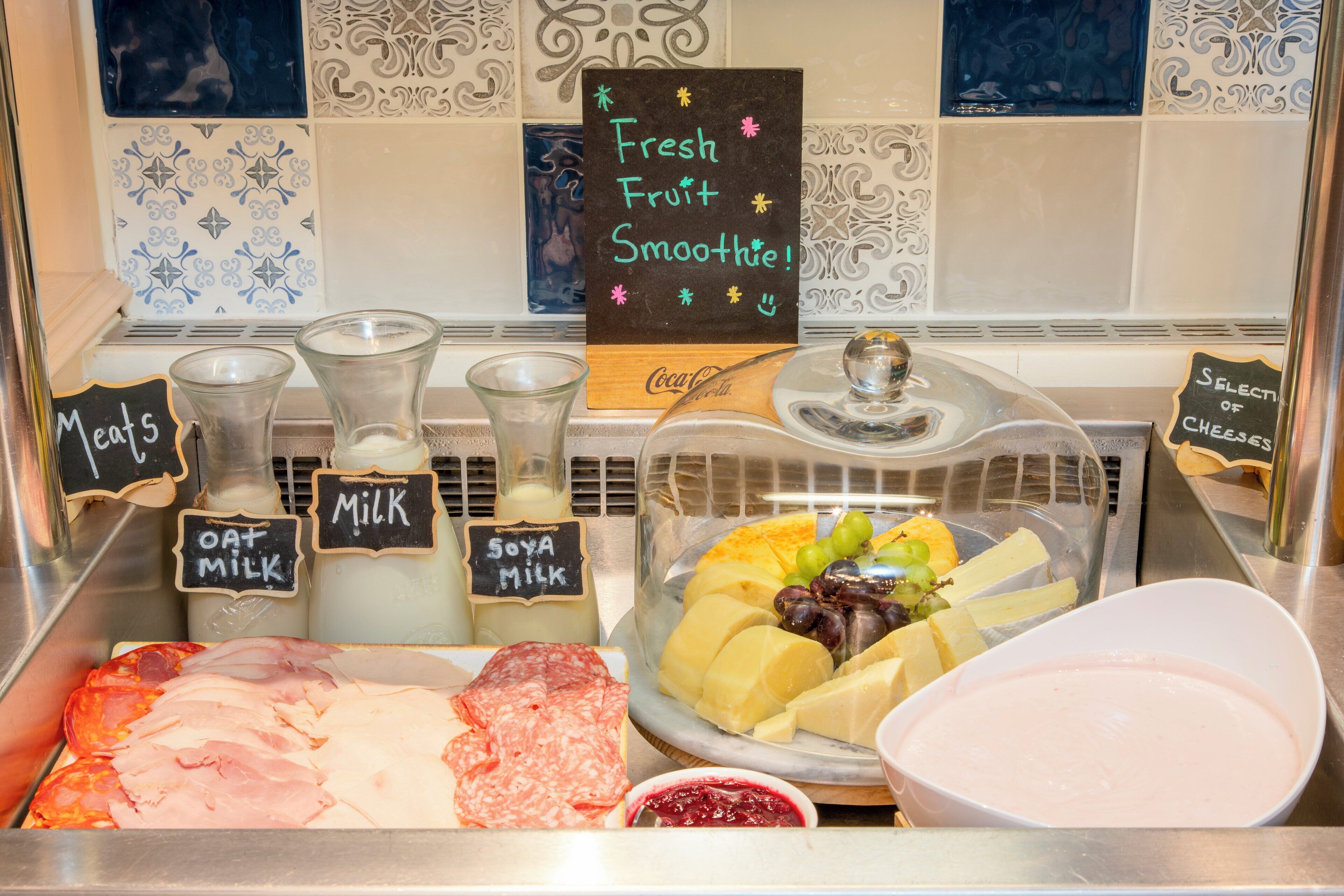 A deli counter with various meats, cheeses, and a fresh fruit smoothie sign.