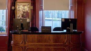 Ein Empfangsschalter mit Holzoptik, ein gerahmtes Theaterbild und ein Fenster mit Blick auf ein Gebäude.