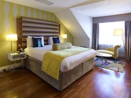 A hotel room with a large bed, bedside lamps, a desk, and a chair.
