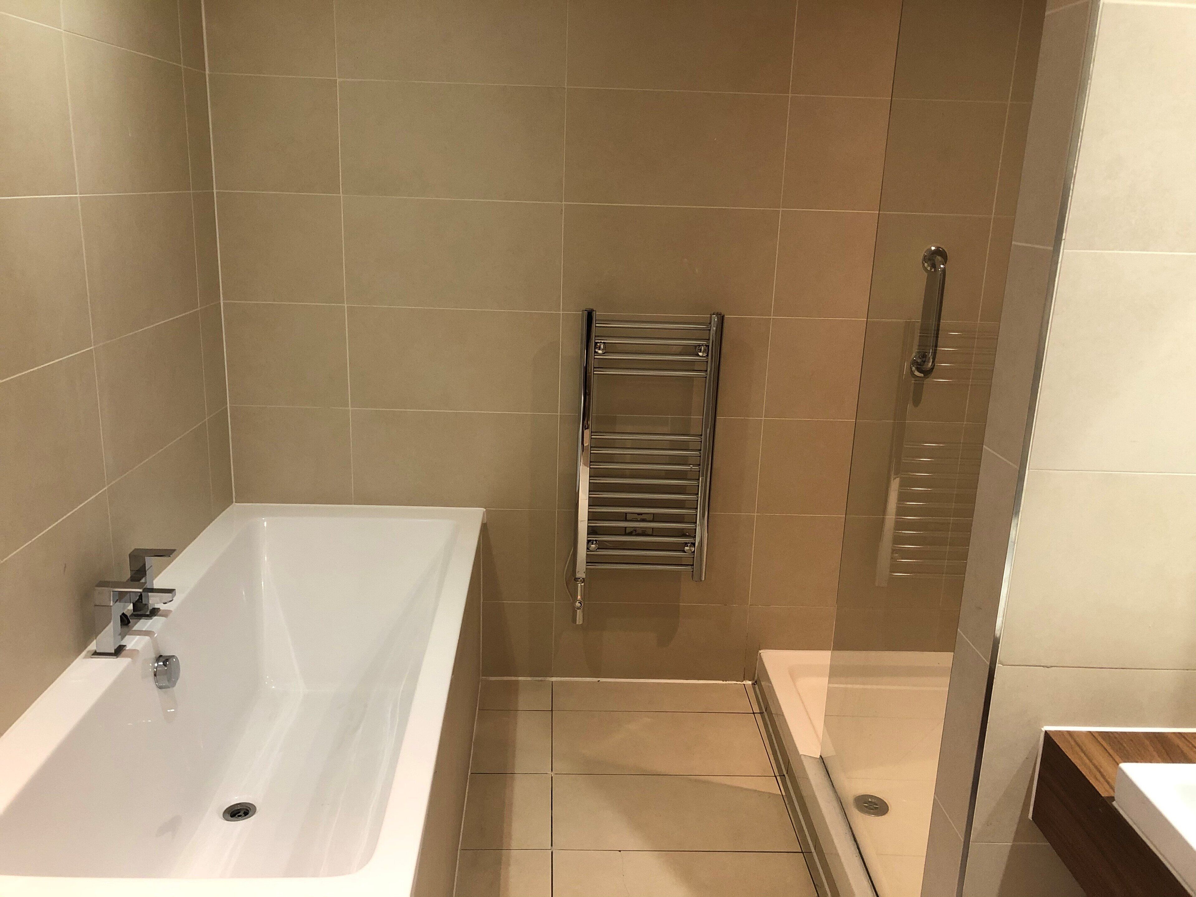 A bathroom with a bathtub, a glass shower enclosure, and a towel rack.