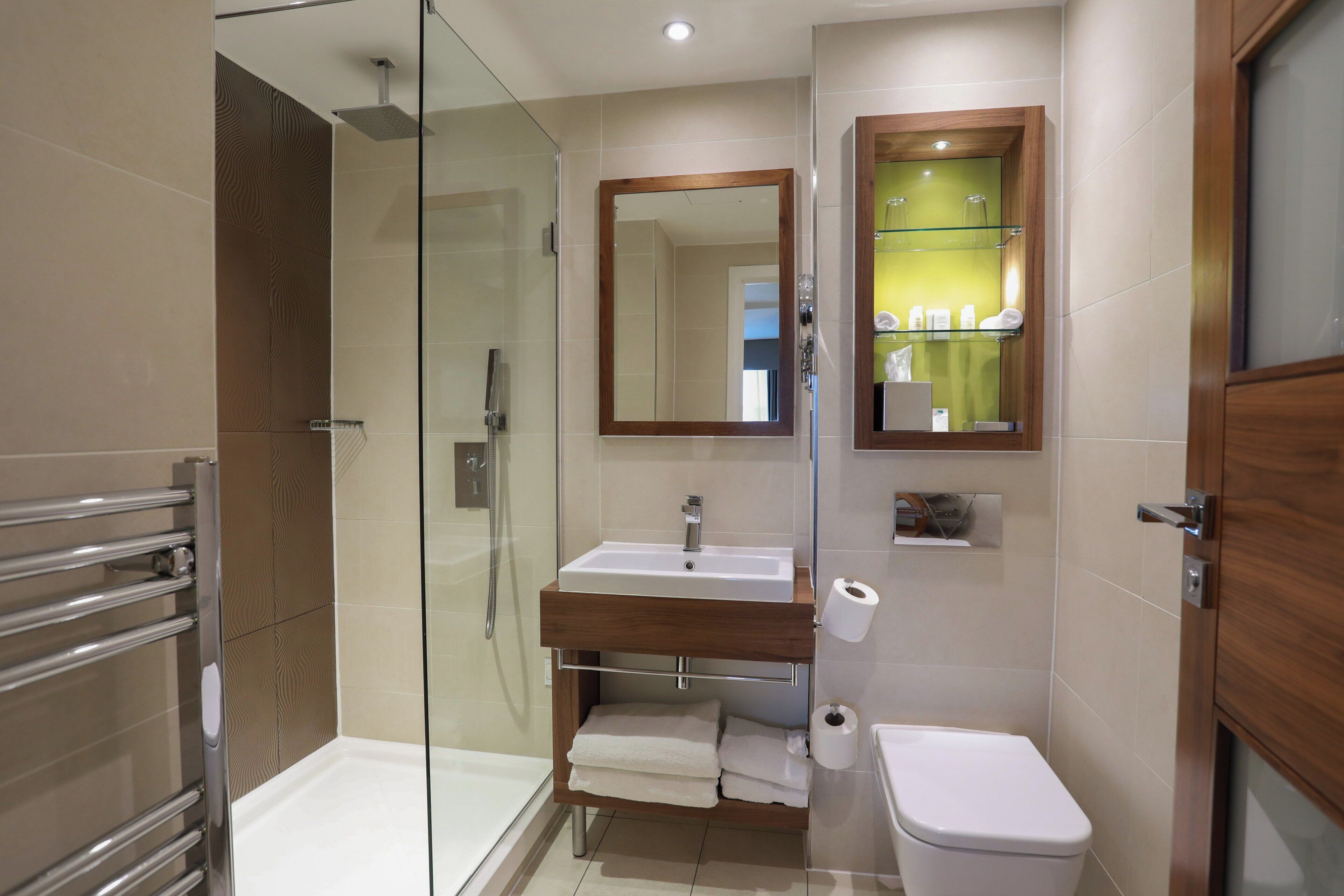 A modern bathroom with a glass-enclosed shower, a wooden vanity with a sink, and a toilet.
