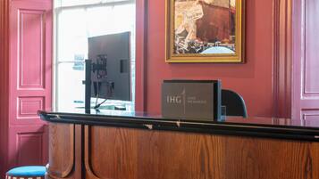 Ein Empfangsschalter mit einem Computer, ein gerahmtes Bild an der Wand und ein Schild mit der Aufschrift 'IHG ONE REWARDS'.
