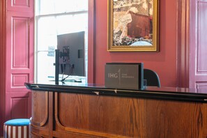 A reception desk with a computer, a framed picture on the wall, and a sign that reads "IHG ONE REWARDS". - Hotel Indigo Edinburgh by IHG (Edinburgh)