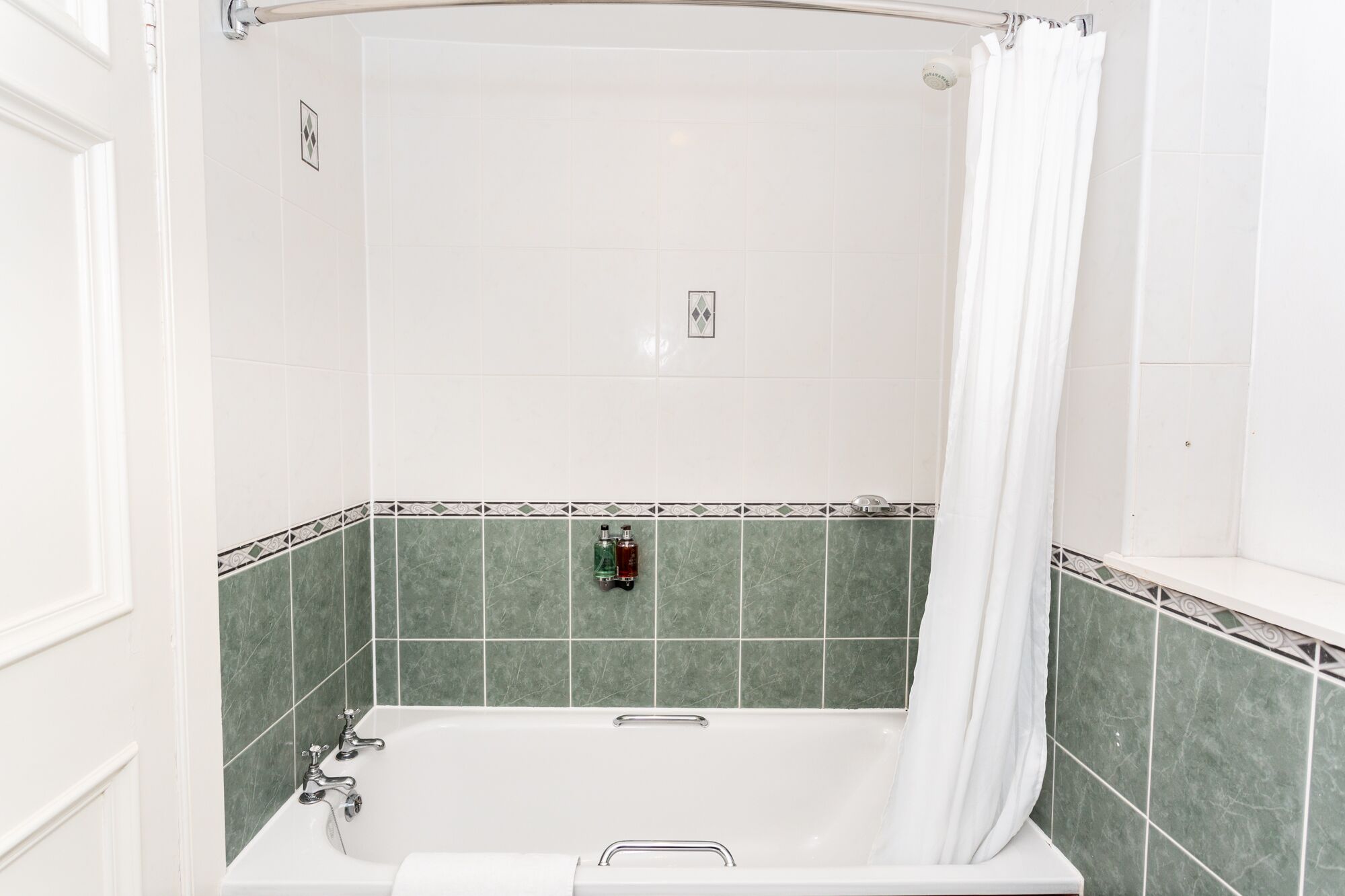A bathroom with a bathtub, a shower curtain, and a hand dryer.