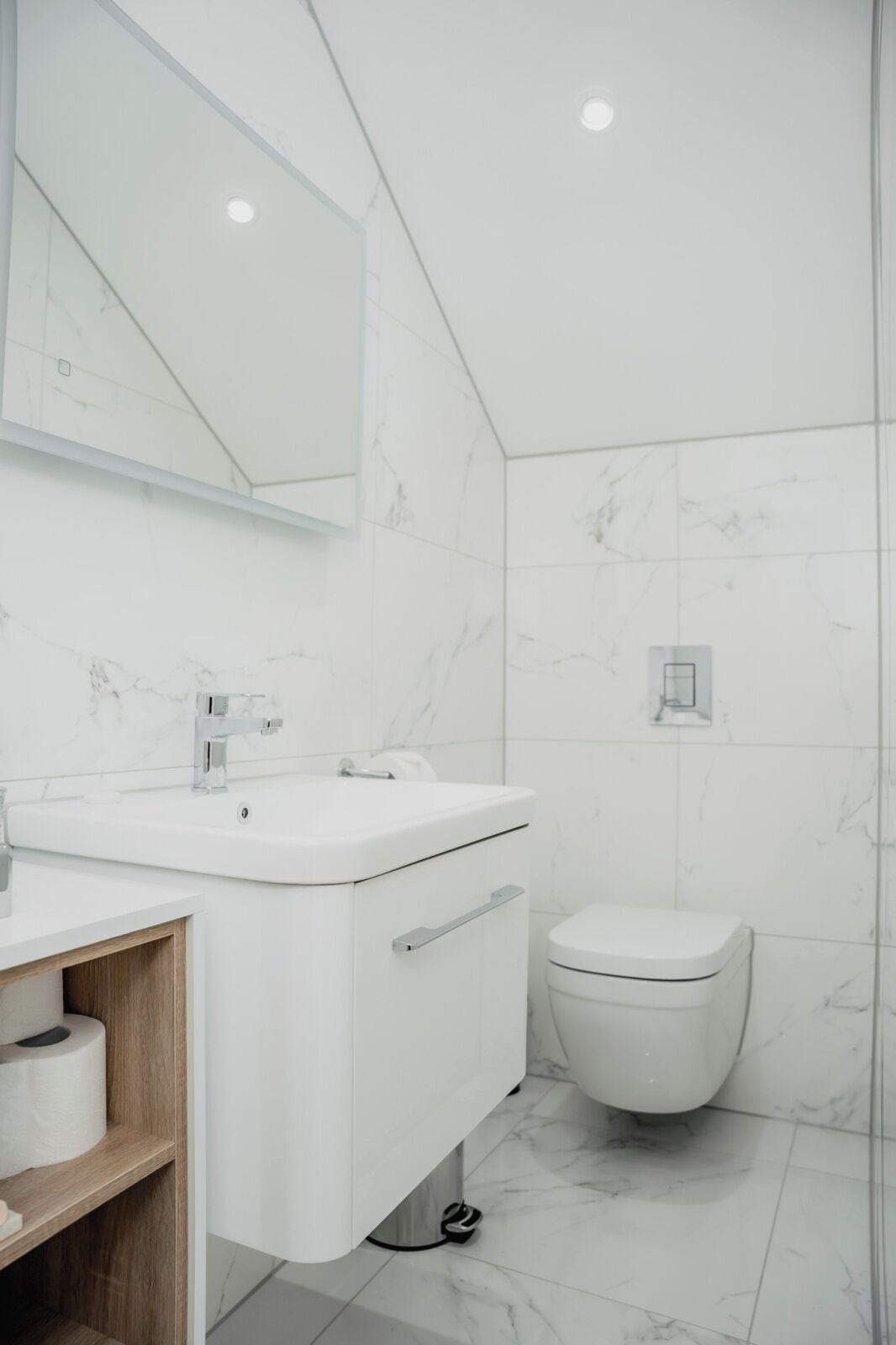 Une salle de bain moderne avec un lavabo blanc, un miroir et des toilettes.