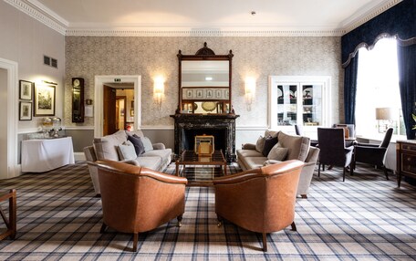 A spacious living room with a fireplace, two leather armchairs, a sofa, and a coffee table.