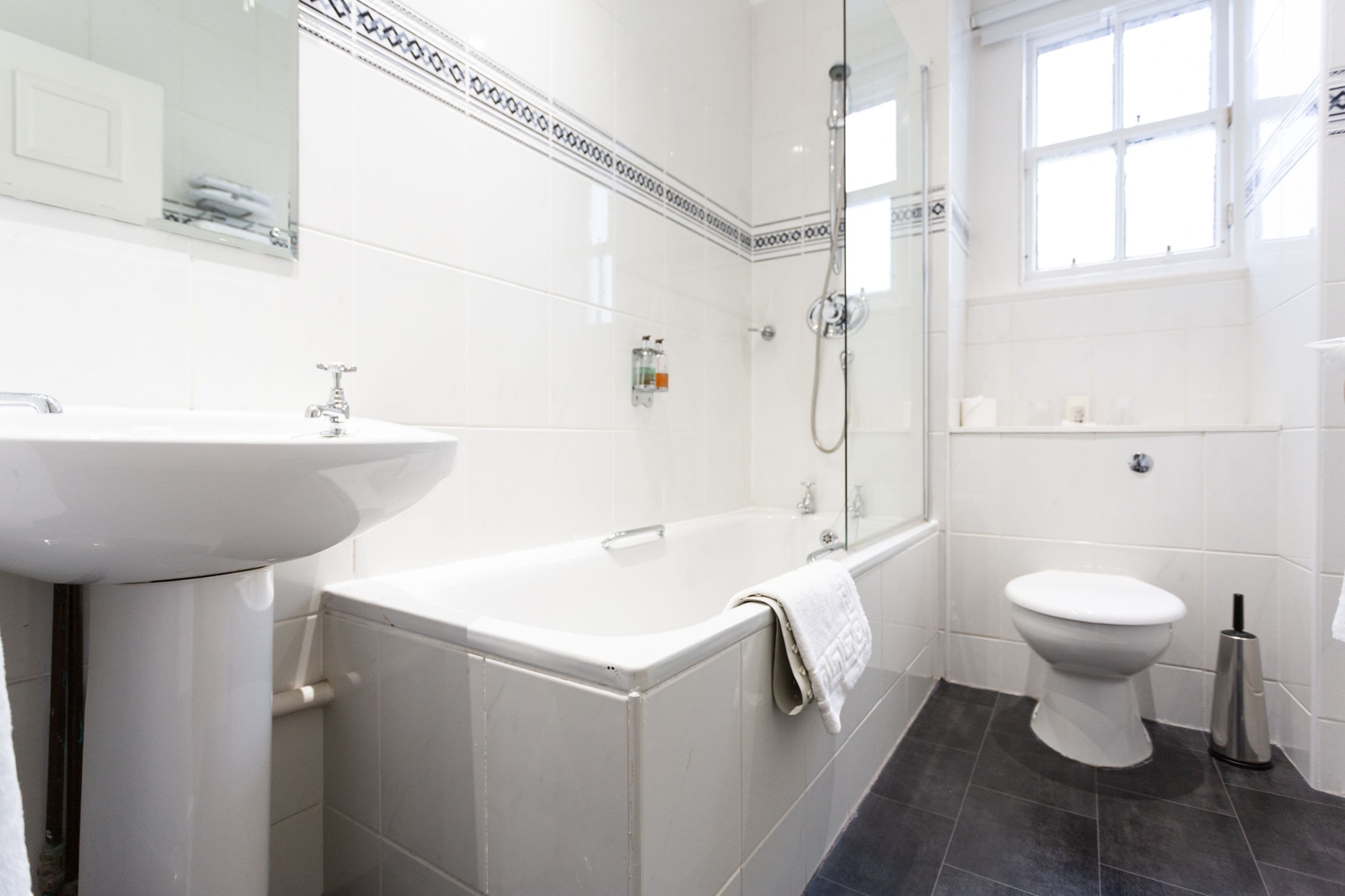 Un baño moderno con lavamanos, bañera y retrete blancos.