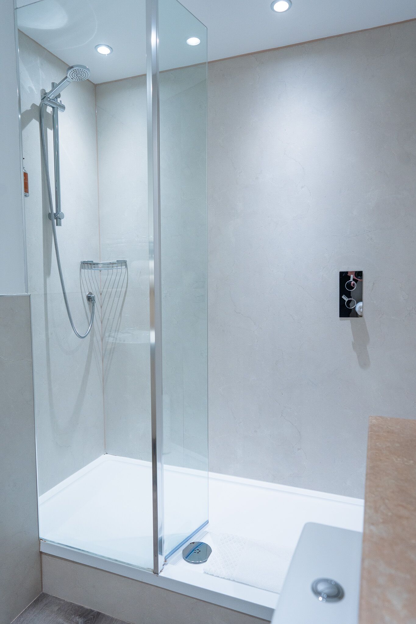 A modern bathroom with a glass-enclosed shower, a visible control panel, and a clean, minimalist design.