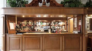 A bar area with wooden paneling, multiple liquor bottles, and a digital screen.