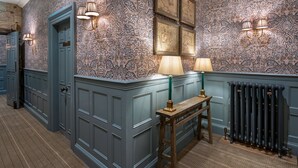 A hallway with patterned wallpaper, a radiator, and wall-mounted lamps. - Beadnell Towers (Chathill)