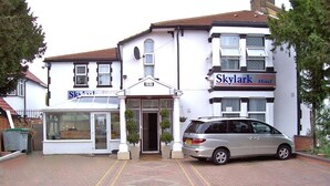 A building with a sign for 'Skylark Motel' and a parked car in front. - Skylark B&B (Hounslow)