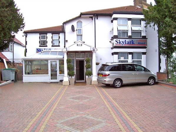 Un edificio con un cartel que dice 'Skylark Motel' y un coche estacionado al frente.