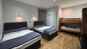 A bedroom with two beds, a wooden bunk bed, a wardrobe, and a radiator. - Skylark B&B (Hounslow)