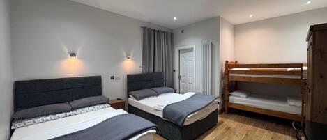 Un dormitorio con dos camas, una litera de madera, un armario y un radiador.