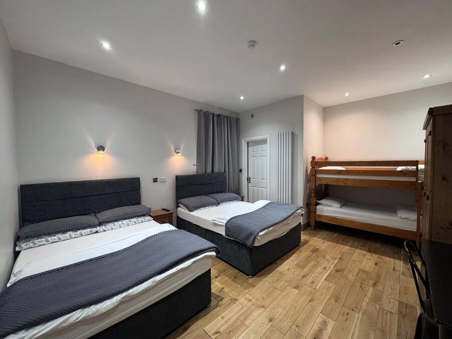 A bedroom with two beds, a wooden bunk bed, a wardrobe, and a radiator.