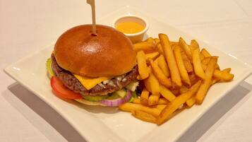 Un plato con una hamburguesa, papas fritas y un pequeño recipiente de salsa.