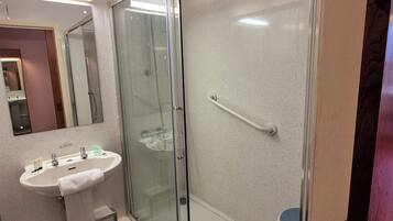 A modern bathroom with a glass-enclosed shower, a pedestal sink, and a mirror above the sink.
