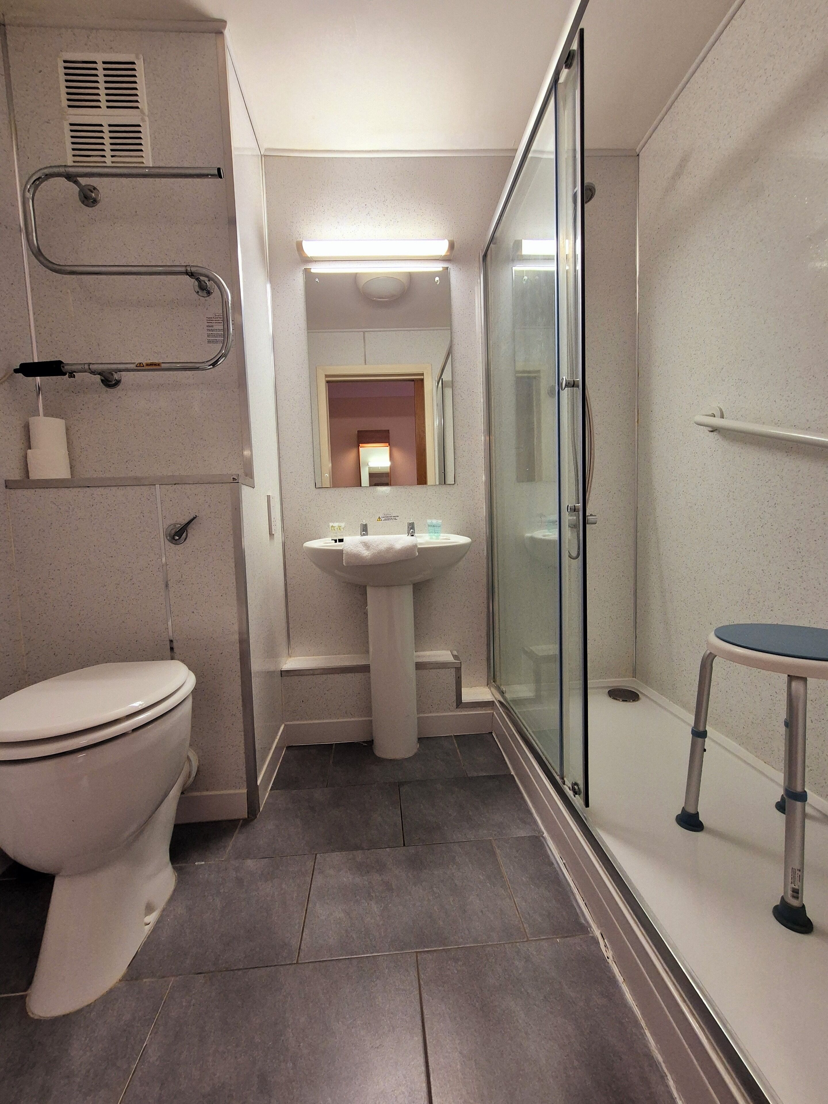 Un baño moderno con inodoro, lavabo y zona de ducha.