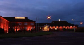A hotel with a prominent sign reading "SUPREME HOTEL" at dusk.