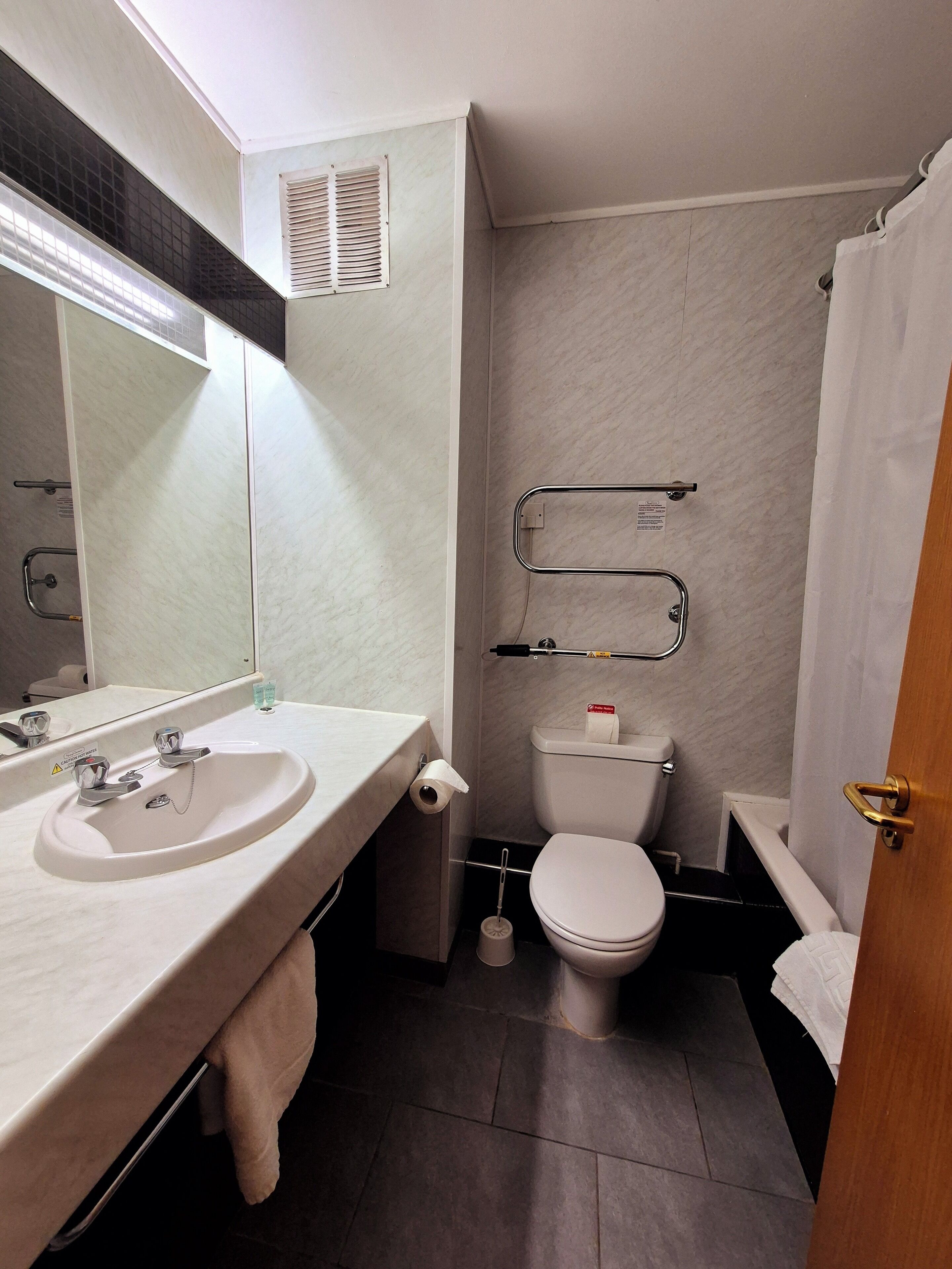 A bathroom with a sink, mirror, toilet, and shower.