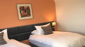 A hotel room with two beds, a headboard, a wall-mounted picture, and a floor lamp.