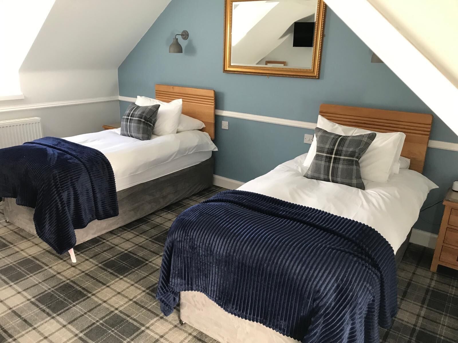 A bedroom with two beds, a large mirror, and a checkered floor.