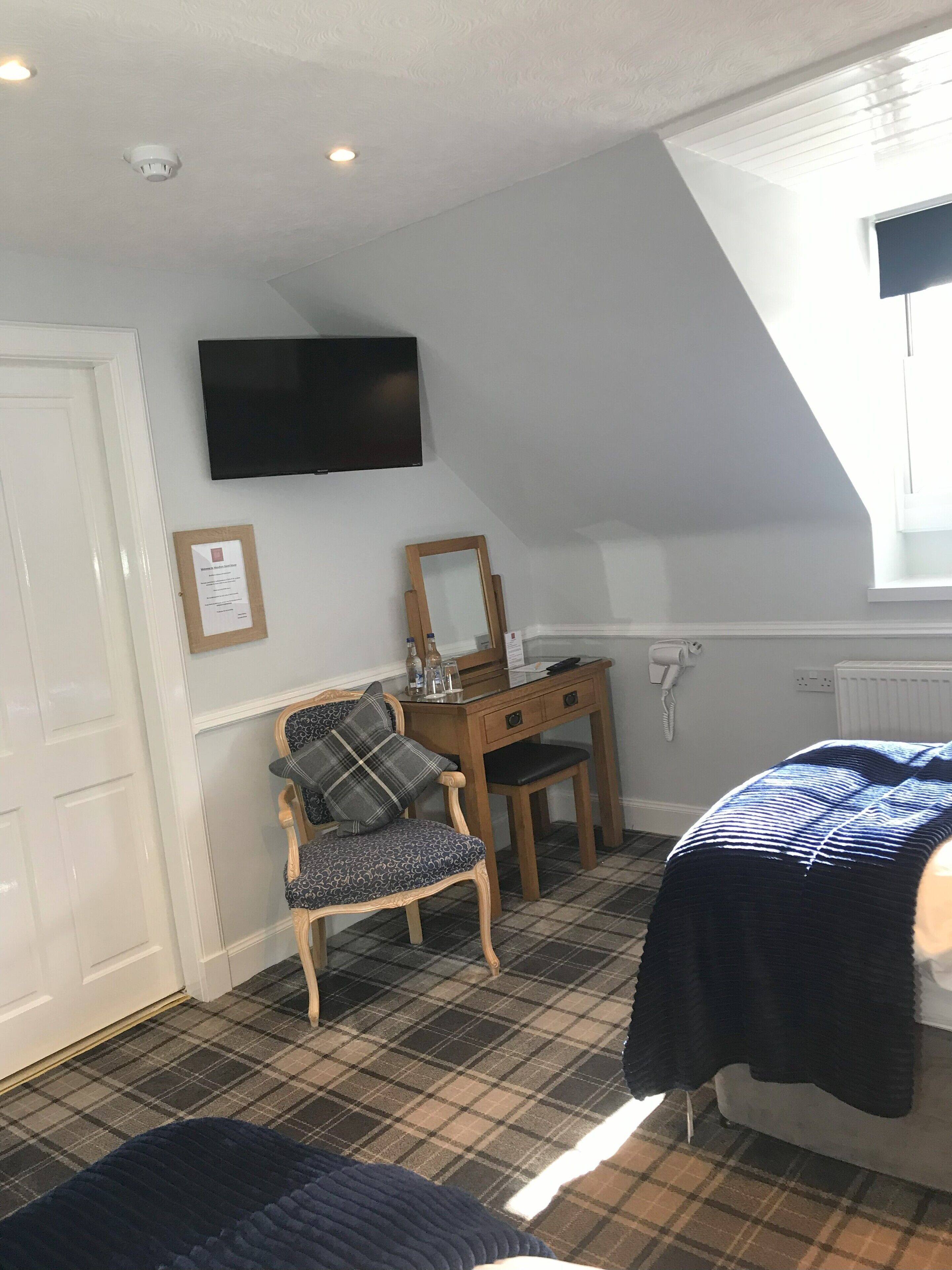 A room with a bed, a desk, a chair, a flat-screen TV, a mirror, and a radiator.