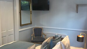 A bedroom with a bed, pillows, a chair, a TV, and a lamp. - Meadhon House (Jedburgh)