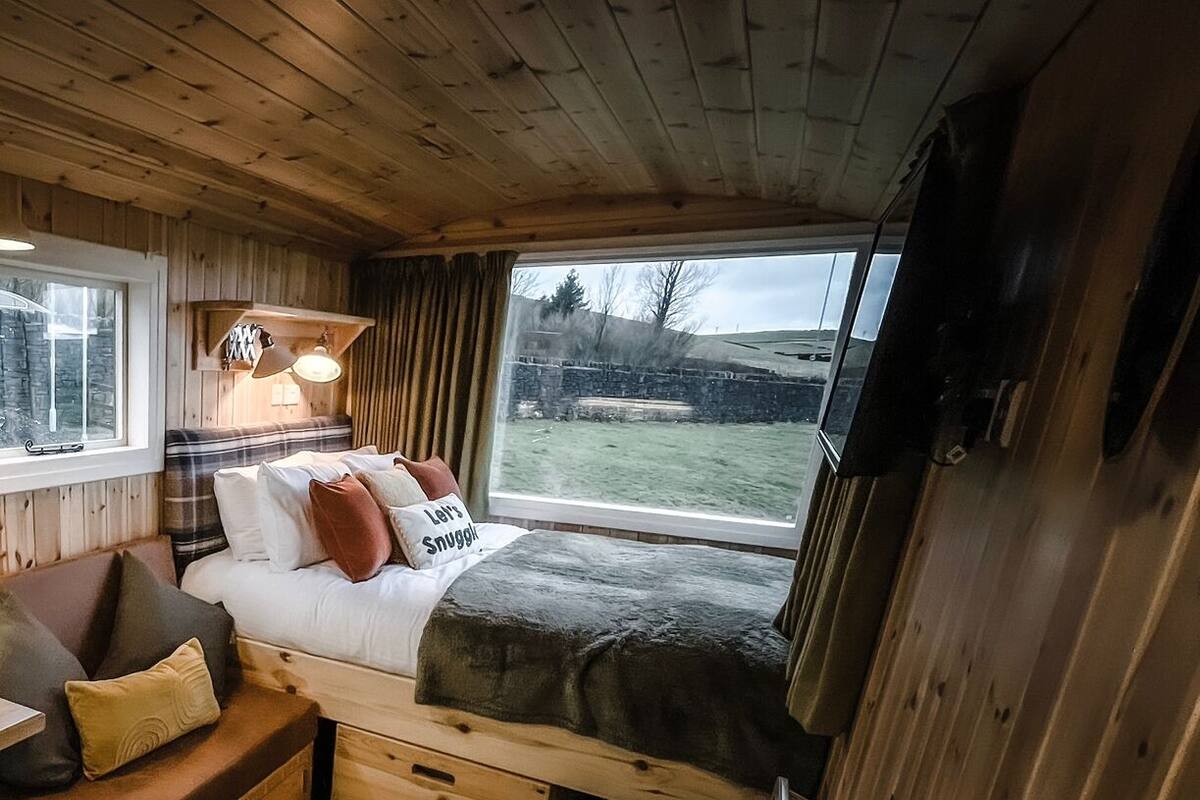Interior acogedor de una cabaña con cama, zona de estar y una mesa con objetos decorativos.