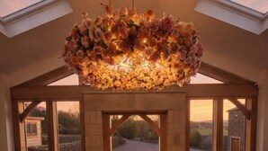 Una habitación amplia con un tragaluz grande, una lámpara de araña floral y vistas a un paisaje rural.