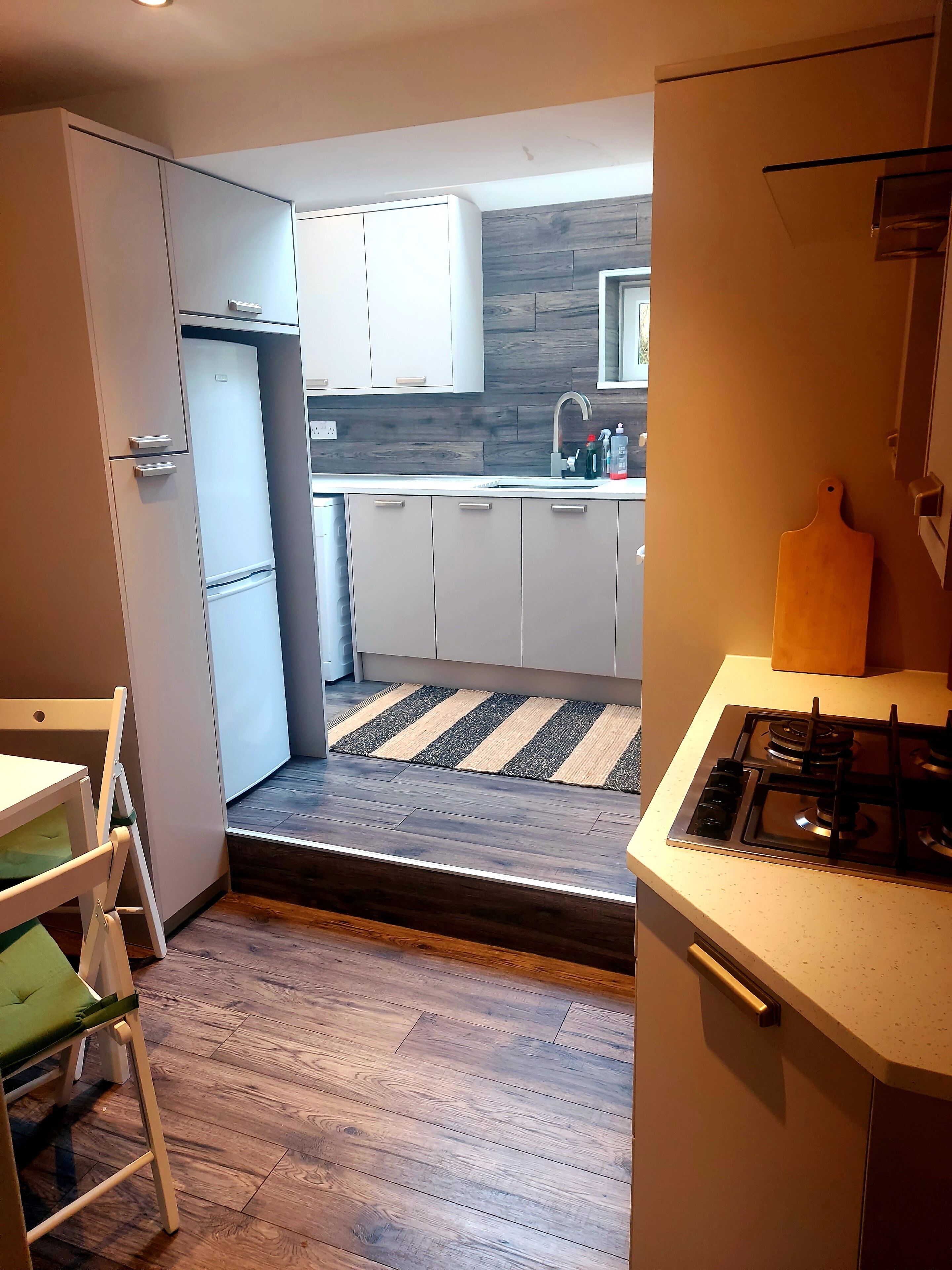 A compact kitchen with a refrigerator, stove, and wooden flooring.