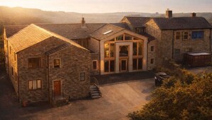 Un edificio de piedra con un hall central y habitaciones más pequeñas, rodeado por un patio de grava.