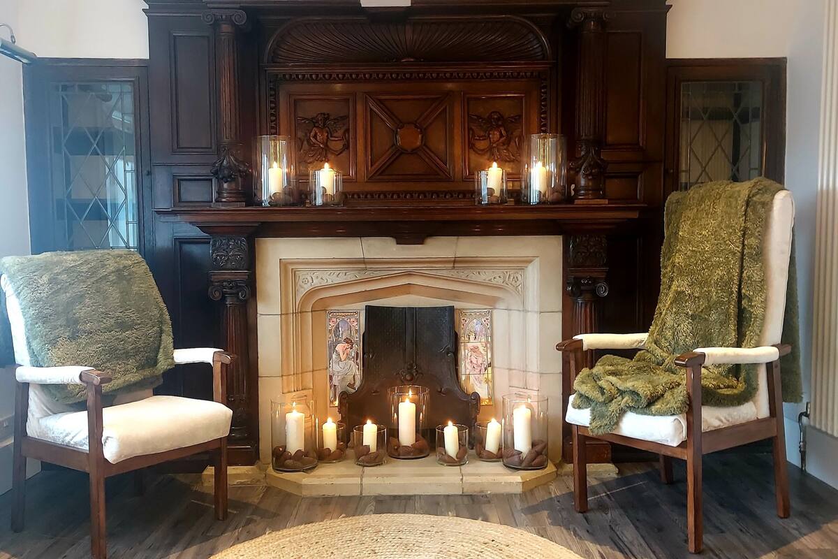 Una habitación con chimenea, dos sillones y una alfombra tejida.