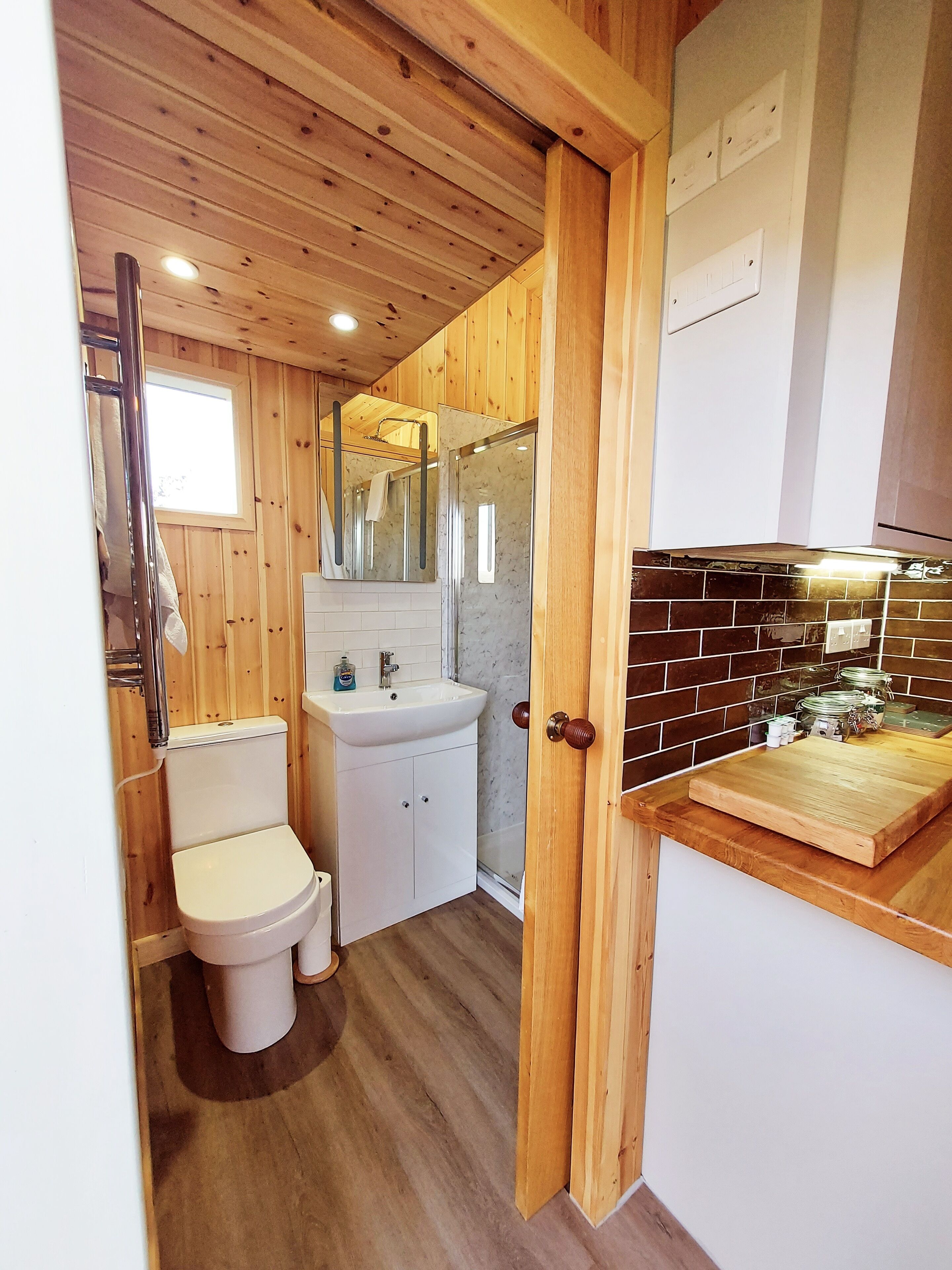Un baño con paneles de madera, que incluye inodoro, lavabo y ducha.