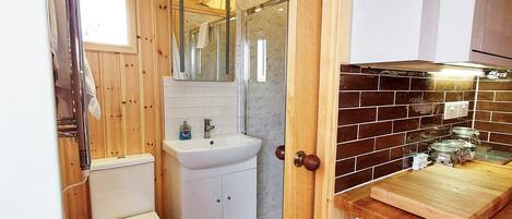 Un baño con paneles de madera, que incluye inodoro, lavabo y ducha.