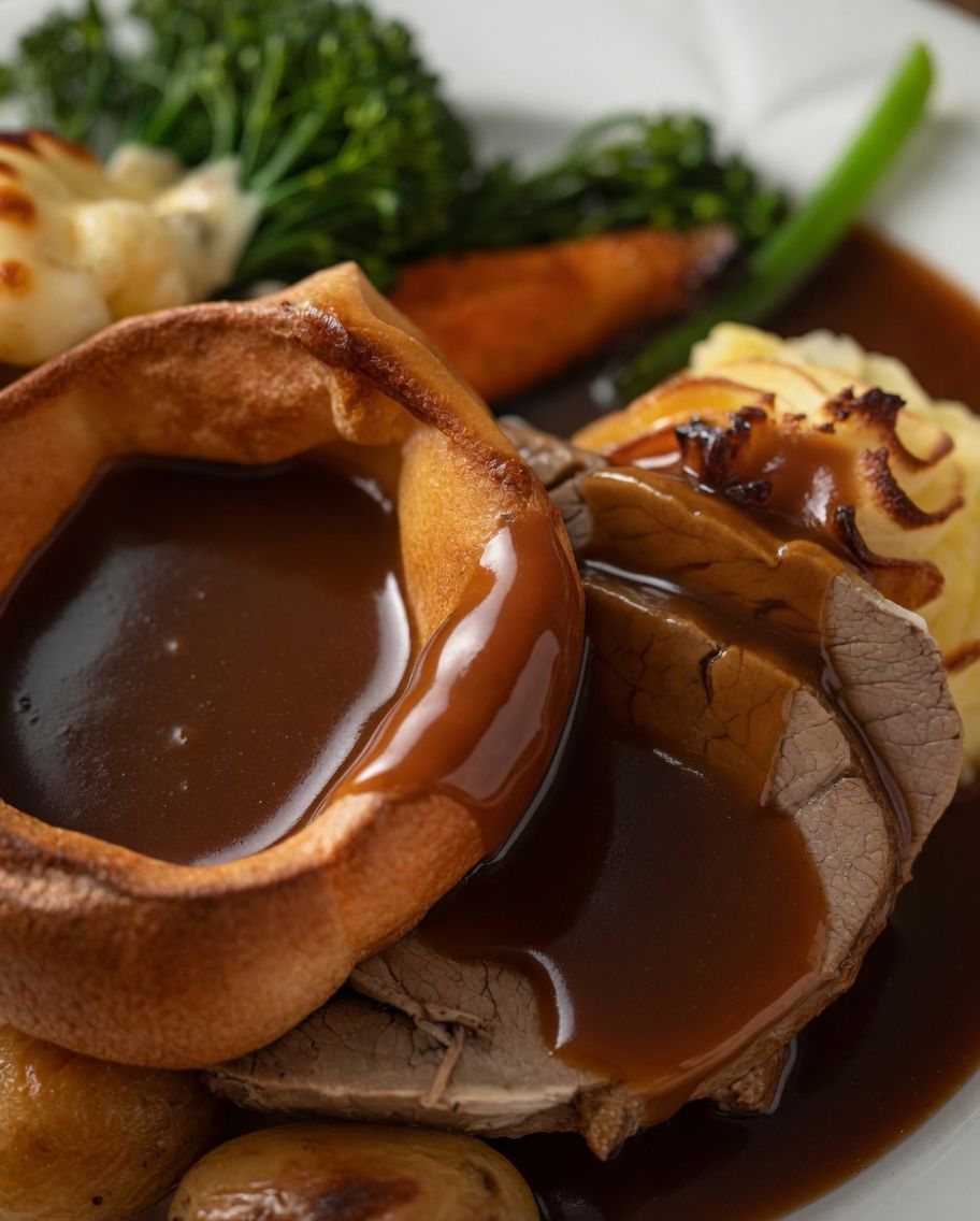A traditional roast dinner with Yorkshire pudding, gravy, and vegetables.