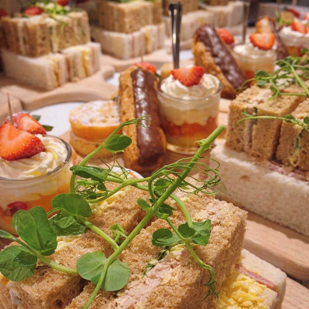 A variety of sandwiches and desserts on a wooden board.